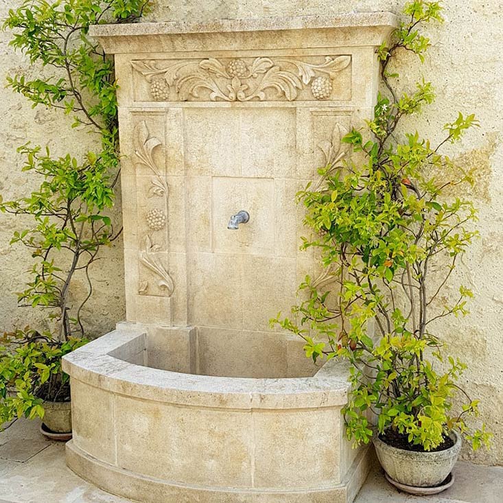 fontaine de jardin en pierre naturelle avec fronton sculpté et corniche moulurée sculpture végétaux fleurs fruits bassin margelle
