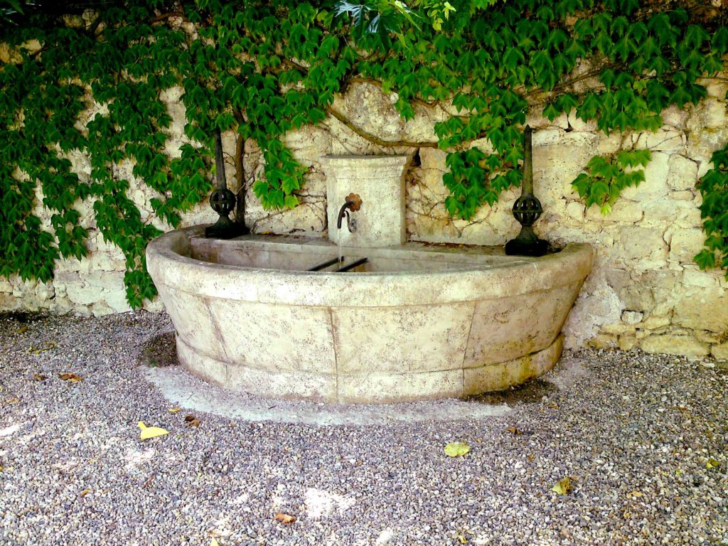 Fontaine en pierre naturelle avec patine ancienne, bassin cintré et margelle gravée