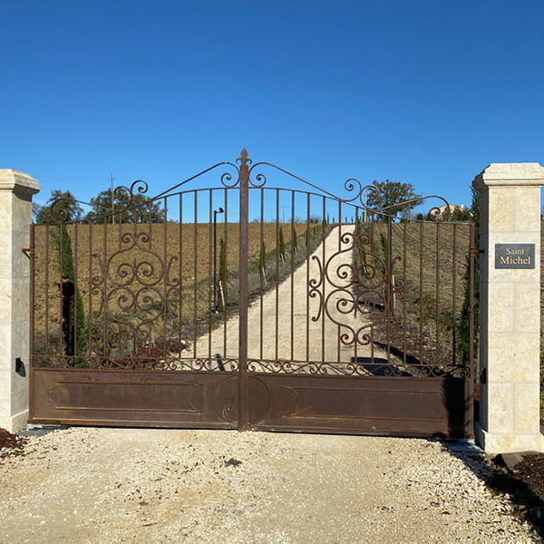 Piliers d'entrée en pierre avec portail en ferronnerie