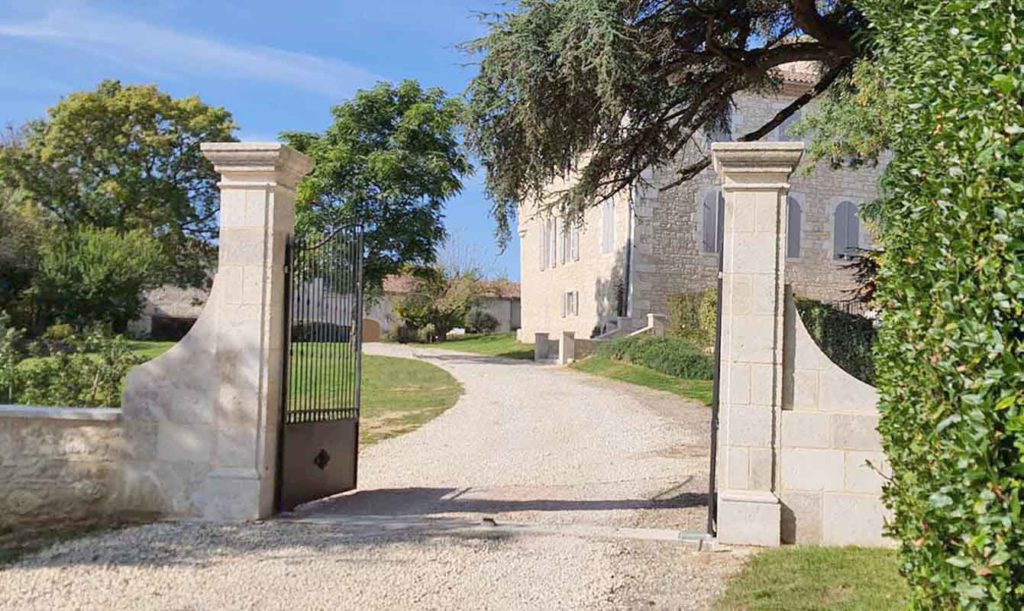 natural stone gate pillars with ironwork grille and moulded capitals