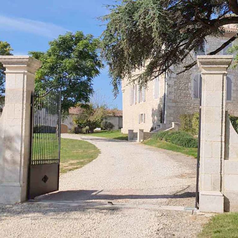 natural stone gate pillars with ironwork grille and moulded capitals