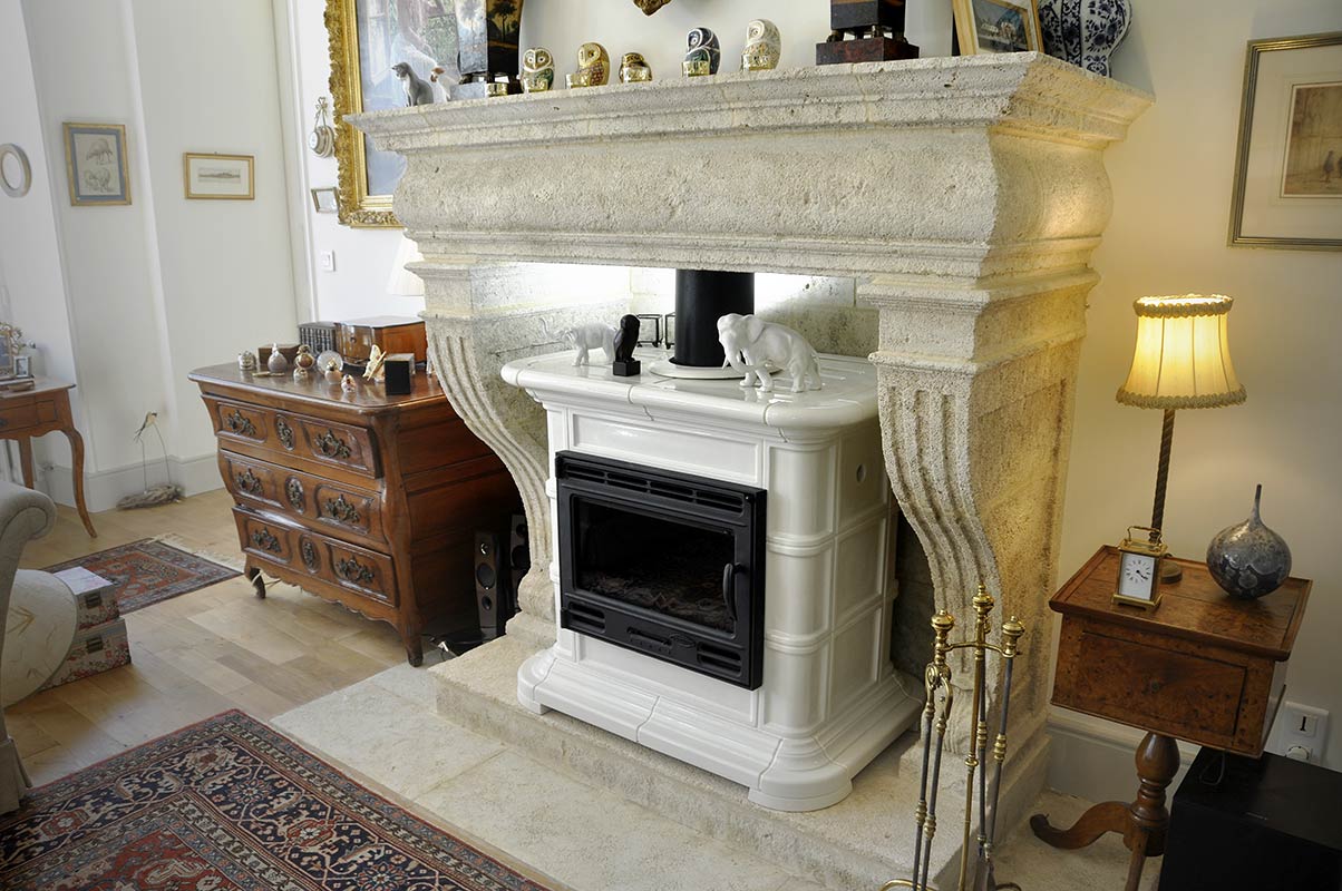 Custom-made natural stone mantel with fluted jambs and moulded lintel, integration of a stove