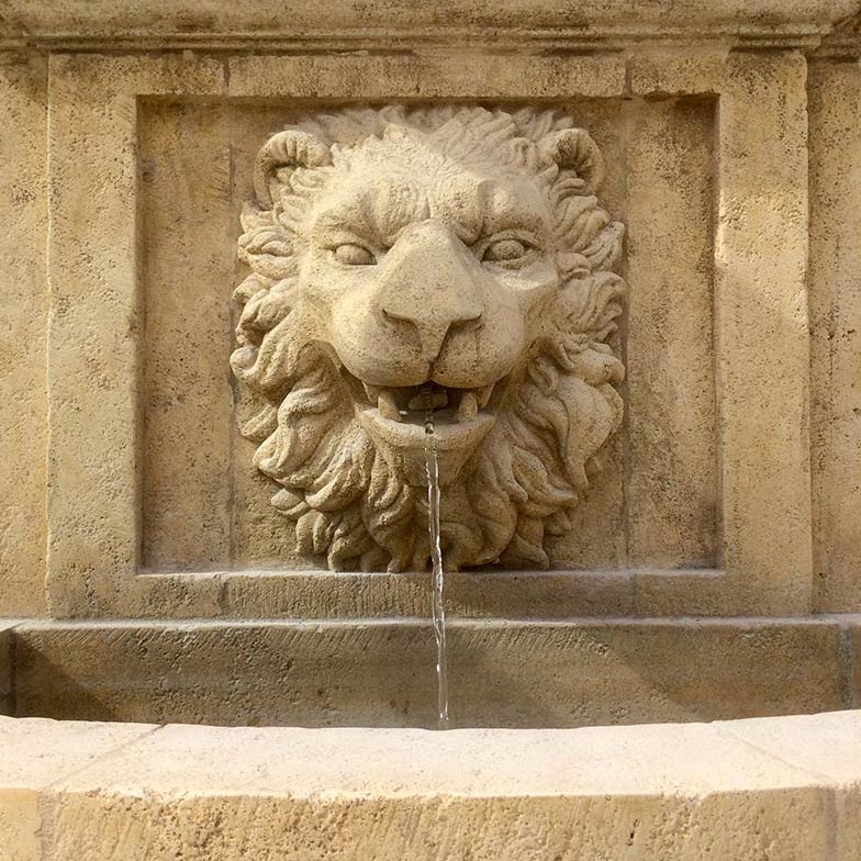 fontaine de jardin en pierre de taille avec tête de lion sculptée sur le fronton
