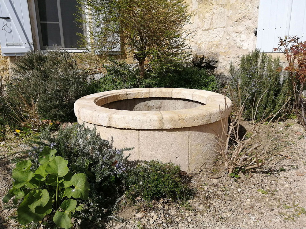 habillage d'un puits buse en béton avec un placage en pierre naturelle réalisé sur mesure margelle épaisse en pierre de taille