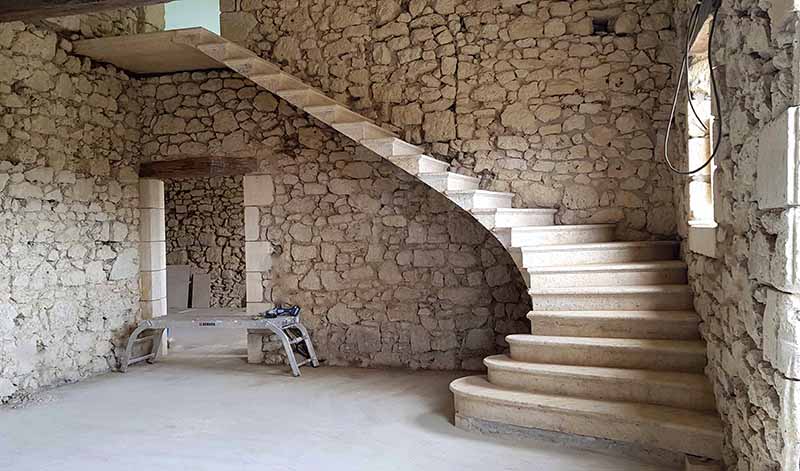 escalier suspendu en pierre de taille sur mesure quart tournant marches balancées ancrage mur palier pierre calcaire naturelle beige création rénovation escalier tournant