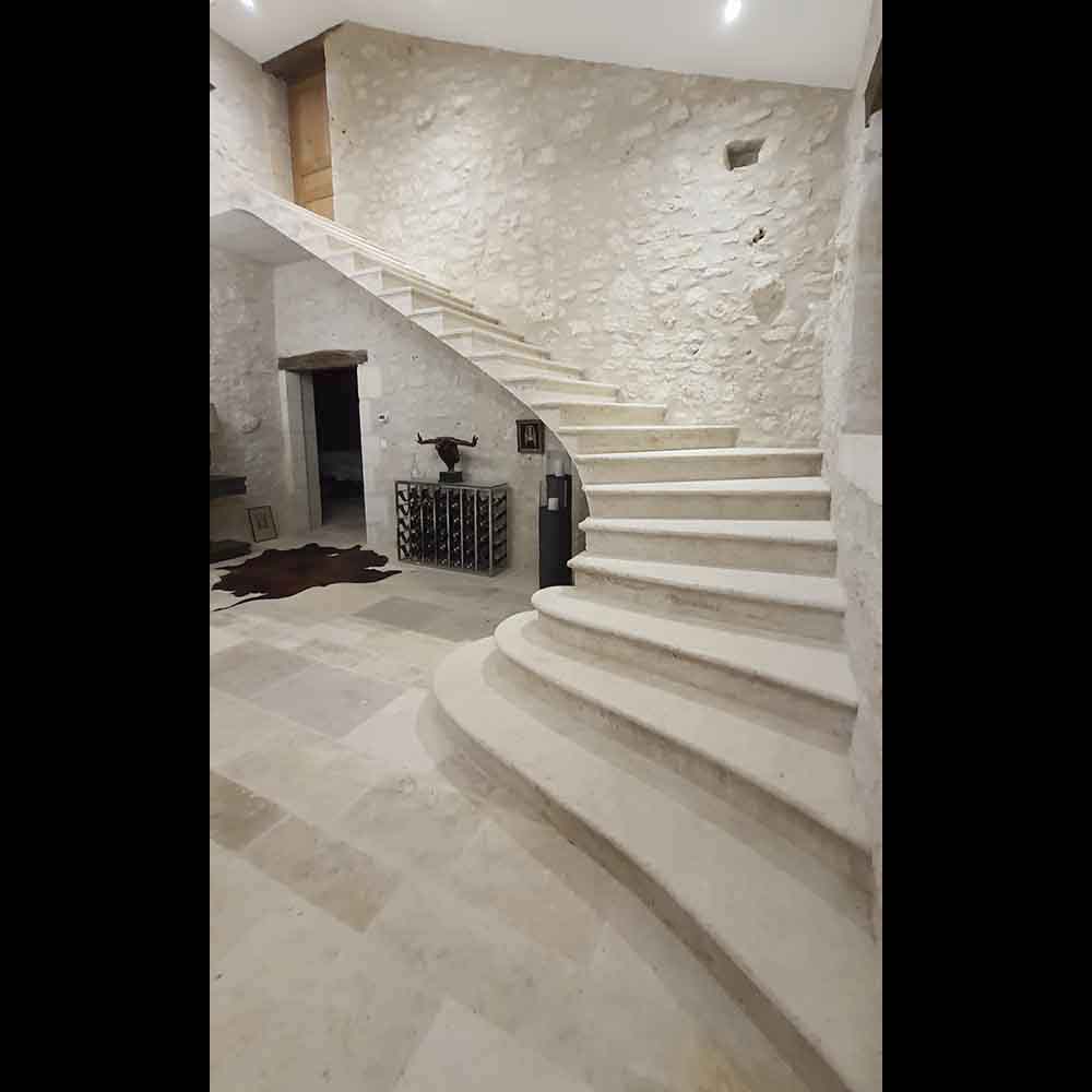 grand escalier en pierre de taille sur mesure forme suspendue marches balancées ancrage mur beige palier