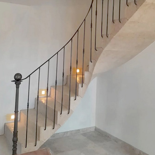 escalier en pierre de taille calcaire beige quart-tournant rampe garde-corps ferronnerie fer forgé rénovation patine belle demeure marches massives voûte sarrasine