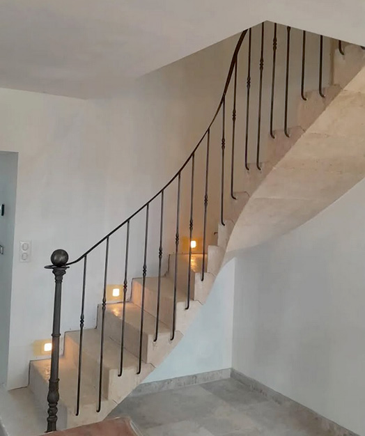 Escalier réalisé sur mesure en pierre calcaire massive avec des marches balancées ancrées dans le mur et une belle envolée.